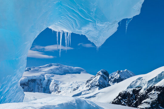 View from under a blue ice archway of an iceberg.
