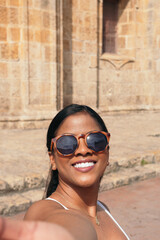 Young woman in Cartagena, Colombia taking a selfie with the city in the background.