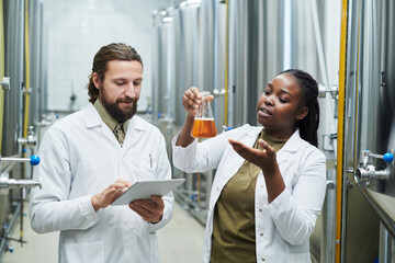 Laboratory workers checking quality of beer produced at brewery