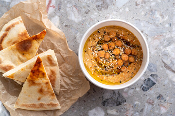 Pita with hummus over light background. Top view, flat lay. Food for delivery.