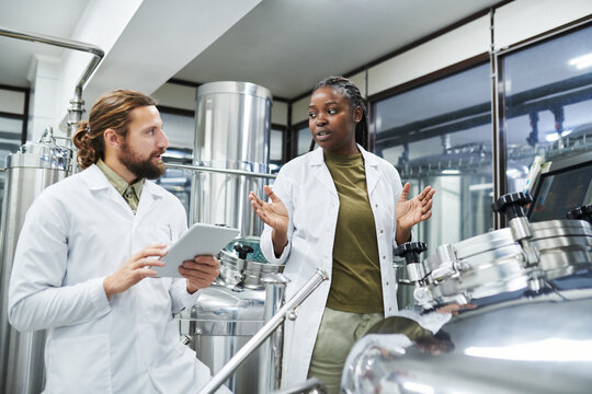 Diverse team of technologists checking equipment at brewery