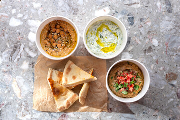 Pita with assorted traditional greek dips, tzatziki, vegetable caviar, hummus over light background.