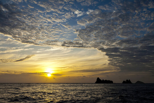 Silhouettes of distant islands under a sunrise sky.