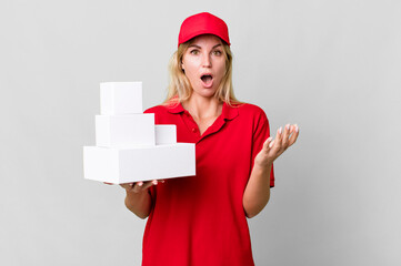 caucasian blonde woman feeling extremely shocked and surprised. delivery boxes