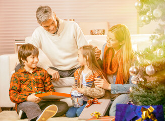 Happy smiling caucasian family at home for Christmas unwrapping Christmas gifts.