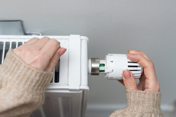 Woman holding temperature knob of heating radiator