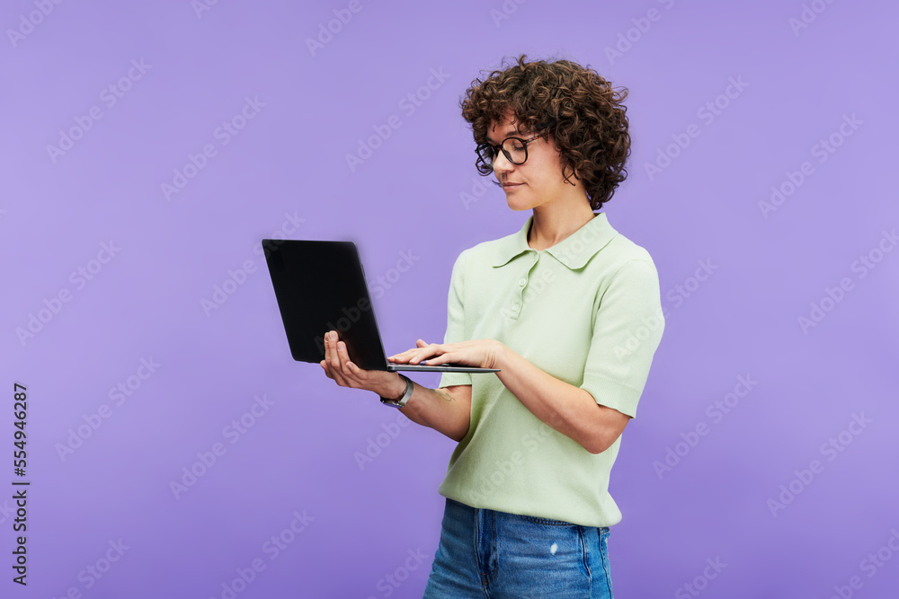 Aufkleber young serious brunette woman in casualwear typing on laptop keyboard while networking on studying on