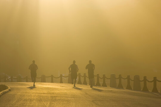 Runners in fog at dusk near the Golden Gate Bridge.; San  Francisco, California.