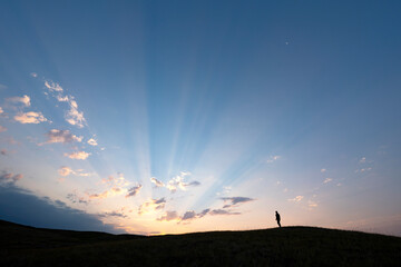 Silhouetted person watching the sunrise over the prairies in rural Saskatchewan, Grasslands National Park; Saskatchewan, Canada