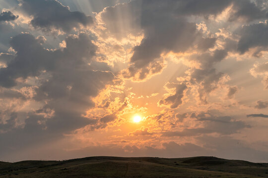 Beautiful sunrise over the prairies of Saskatchewan. Beams of light shine through the clouds, Grasslands National Park; Saskatchewan, Canada