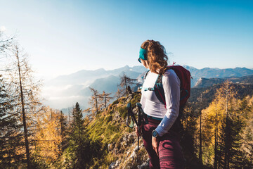 Waist up woman hiker looking away from the camera at a view of the sunny autumn mountains in the...