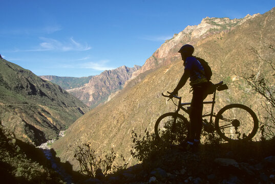 A biker pauses at the rim of a canyon.; Batopillas Canyon, Sierra Madre Mountains, Mexico.