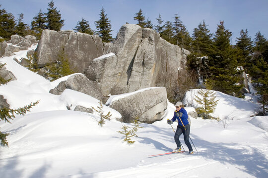 A woman cross-country skiing past big rocks in West Virginia; Dolly Sods, West Virginia