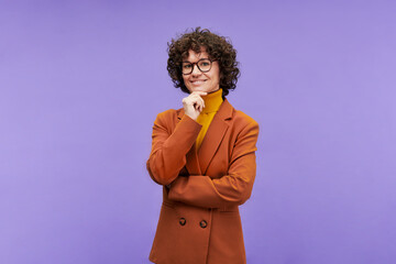 Happy young elegant teacher in stylish formalwear and eyeglasses standing in front of camera in isolation against violet background