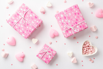Obraz na płótnie Canvas Saint Valentine's Day concept. Top view photo of pink present boxes heart shaped plate with sprinkles marshmallow and candles on isolated white background