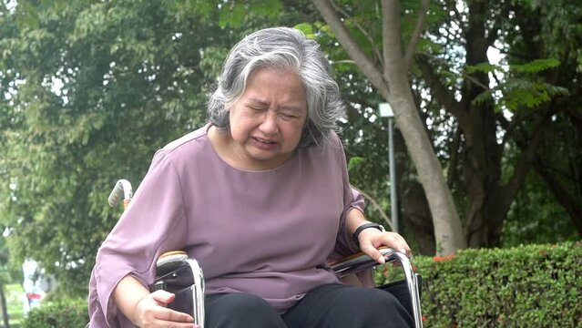 Asian elderly woman patients sitting in a wheelchair, is suffering from angina Due to heart disease. to people elderly heart disease and health care concept.