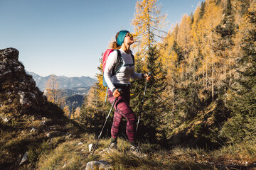 Cheerful caucasian woman hiking on a sunny autumn day, soaking in the mountain sun 