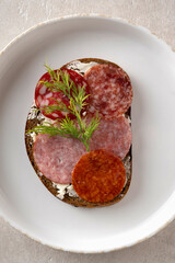 closeup sandwich with dried sausage, brown bread, butter