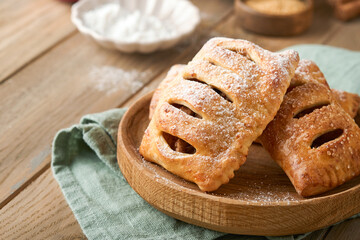 Hand pies. Mini puff pastry or hand pies stuffed with apple and sprinkle sugar powder in wooden plate. Homemade pie snack with crust for breakfast rustic photo.  Copy space.
