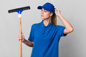 caucasian blonde woman smiling happily and daydreaming or doubting. windows washer concept