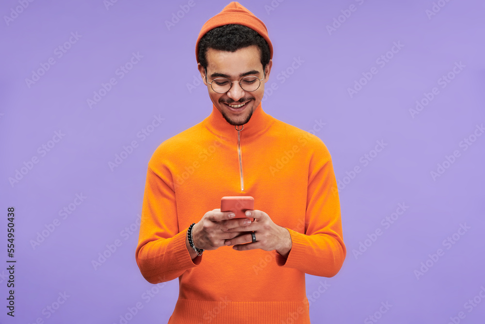 Aufkleber smiling multi-ethnic guy in orange casualwear texting in smartphone or reading advert message or ord