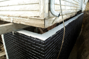 Black tar waterproofing on a newly-poured basement wall; Otoe, Nebraska, United States of America