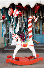 Fototapeta na wymiar Christmas gifts and horse toy near cafe. Modern Christmas decor in city street. Winter holidays in Europe. Merry Christmas in Ukraine.
