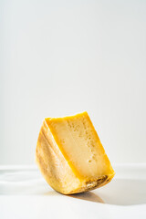 a piece of parmesan or pecorino cheese on a white table. still life