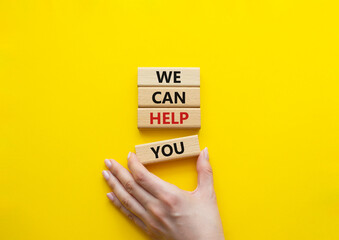 We can help you symbol. Concept words We can help you on wooden blocks. Beautiful yellow background. Businessman hand. Business and We can help you concept. Copy space