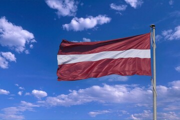 The flag of the state of Latvia on the background of the sunny sky.