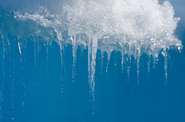 Icicles melting and dripping against a blue sky on the Antarctic Peninsula, near the Antarctic Circle; Antarctica