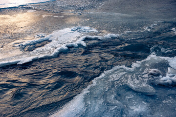 Frozen ice and snow in river side. Spring thawed patch in the ice