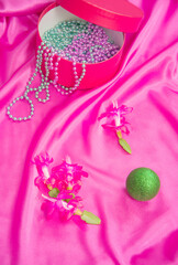 Gift box with jewelry, green Christmas ball and flowers. Magenta color background.