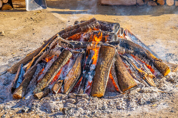 Top of a large circular bonfire packed with firewood on the sides that smoke comes from the wooden logs in a popular village festival for typical rural celebration