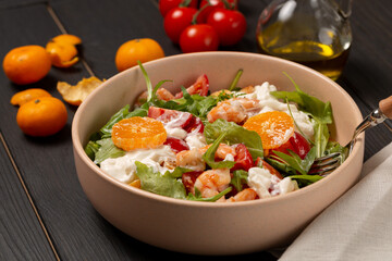 Fresh light salad with arugula, shrimp, tangerines, strachatella cheese, cherry tomatoes