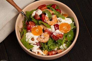 Fresh light salad with arugula, shrimp, tangerines, strachatella cheese, cherry tomatoes