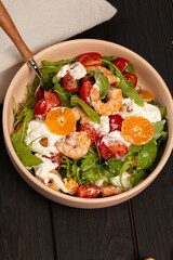 Fresh light salad with arugula, shrimp, tangerines, strachatella cheese, cherry tomatoes