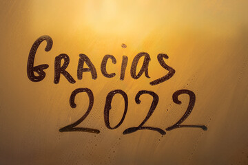 lettering thanks in Spanish Gracias and numbers 2022 paint with finger with streaks of water on...