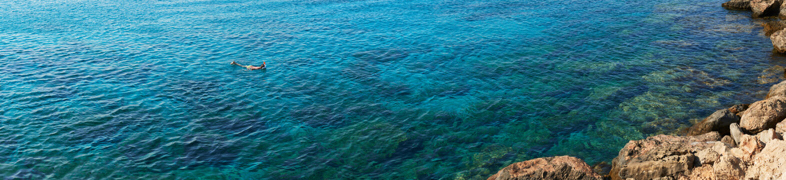 Panoramic photograph of child snorkeling in Mediterranean sea.
