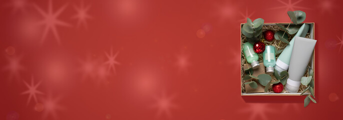 Beauty box with face and body care products on  red background. Tubes with cream and lotion, soap, eucalyptus leaves. Organic cosmetics gift