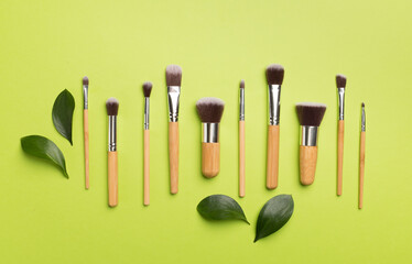Natural biodegradable makeup brushes on color background, top view