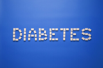 Diabetes word made from sugar cubes on blue background