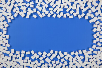 Frame made from sugar cubes on blue background with a copy space