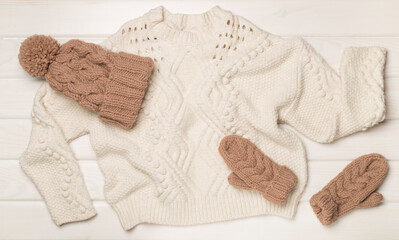 Sweater and winter hat withmittens on light background, top view