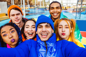 Multiracial group of young happy friends wearing colorful winter jackets meeting outdoors in winter, concepts about youth generation, millennials, teenage and students social gathering