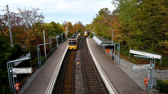 Stuttgart, Germany: October 16, 2022: One outgoing and one approaching yellow streetcar at a station in Stuttgart, Germany.