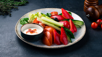 Vegetable salad of tomatoes, sweet peppers, cucumbers, olives, lettuce, celery, parsley, spinach and sauce.