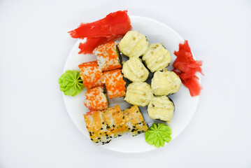 Delicious baked sushi and rolls on a white plate. Delicious breakfast of fish rice rolls and sushi on a white background. Oriental fish cuisine. Japanese cuisine.