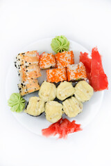 Delicious baked sushi and rolls on a white plate. Delicious breakfast of fish rice rolls and sushi on a white background. Oriental fish cuisine. Japanese cuisine.