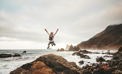 Happy man with backpack jumping on nature background - Successful hiker enjoying freedom climbing...